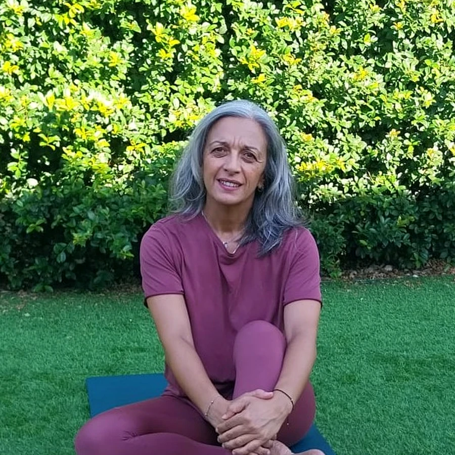 Célia Laranjeira, instrutora de Pilates, sentada num tapete de exercício